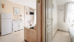 Eine Küche mit Kühlschrank, Schränken, einer Mikrowelle und einem Essbereich mit Tisch und Stühlen.