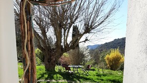 A stone pathway leading to a table and chairs under a tree, surrounded by greenery and hills. - Studio 'Bas Verdon' with Terrace and Private Garden (Allemagne-en-Provence)