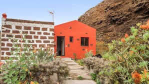 Un bâtiment rouge avec une porte, un mur de briques et un chemin de pierre menant à l’entrée.