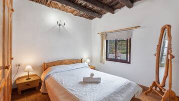 Un dormitorio con una cama de madera, lámparas de noche, una ventana con cortinas y un espejo.