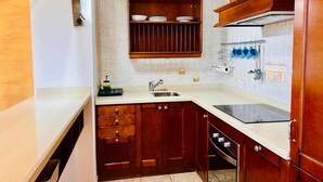 Een keuken met houten kastjes, een inbouwoven, een spoelbak en een afwassysteem.