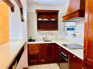 Una cocina con armarios de madera, horno empotrado, lavabo y escurreplatos.
