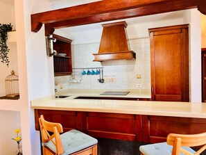 A kitchen with wooden cabinets, a white tiled backsplash, and a central island with chairs.