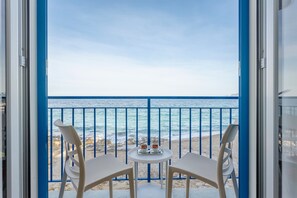 A balcony with a view of the sea, two chairs, and a small table with cups.