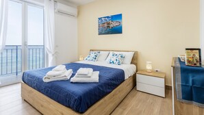 Un dormitorio con una cama, una mesita de noche, una mesa con un libro y un cuadro en la pared.