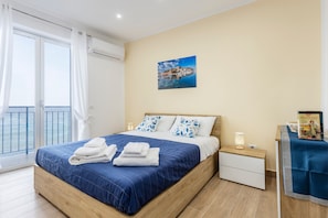 A bedroom with a bed, a nightstand, a table with a book, and a painting on the wall.