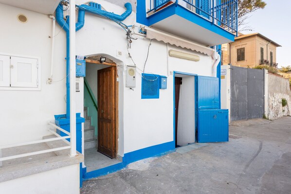 A building with a blue door, a blue window, and a blue balcony railing.