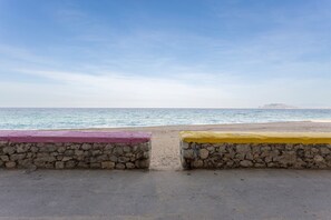 A beach with a stone wall and a paved path leading to the water.
