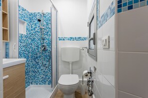 Un baño con ducha, inodoro, lavamanos y paredes con azulejos.