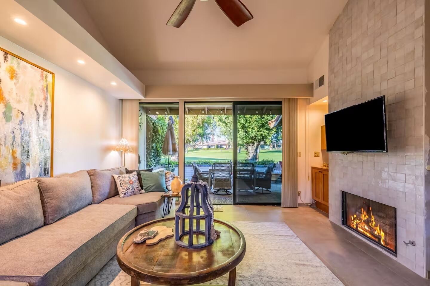 A modern living room with a sofa, a coffee table, a fireplace, and a TV mounted on the wall.