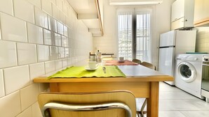 A compact kitchen with a dining area, a washing machine, and a view through a window. - Apartment 'Flaminia' with Balcony and Wi-Fi (Sanremo)