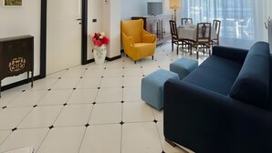 Una sala de estar moderna con un sofá, un sillón amarillo, una mesa de comedor con sillas y un televisor.