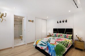 Un dormitorio moderno con cama, mesita de noche, lámpara de pared y zona de ducha.
