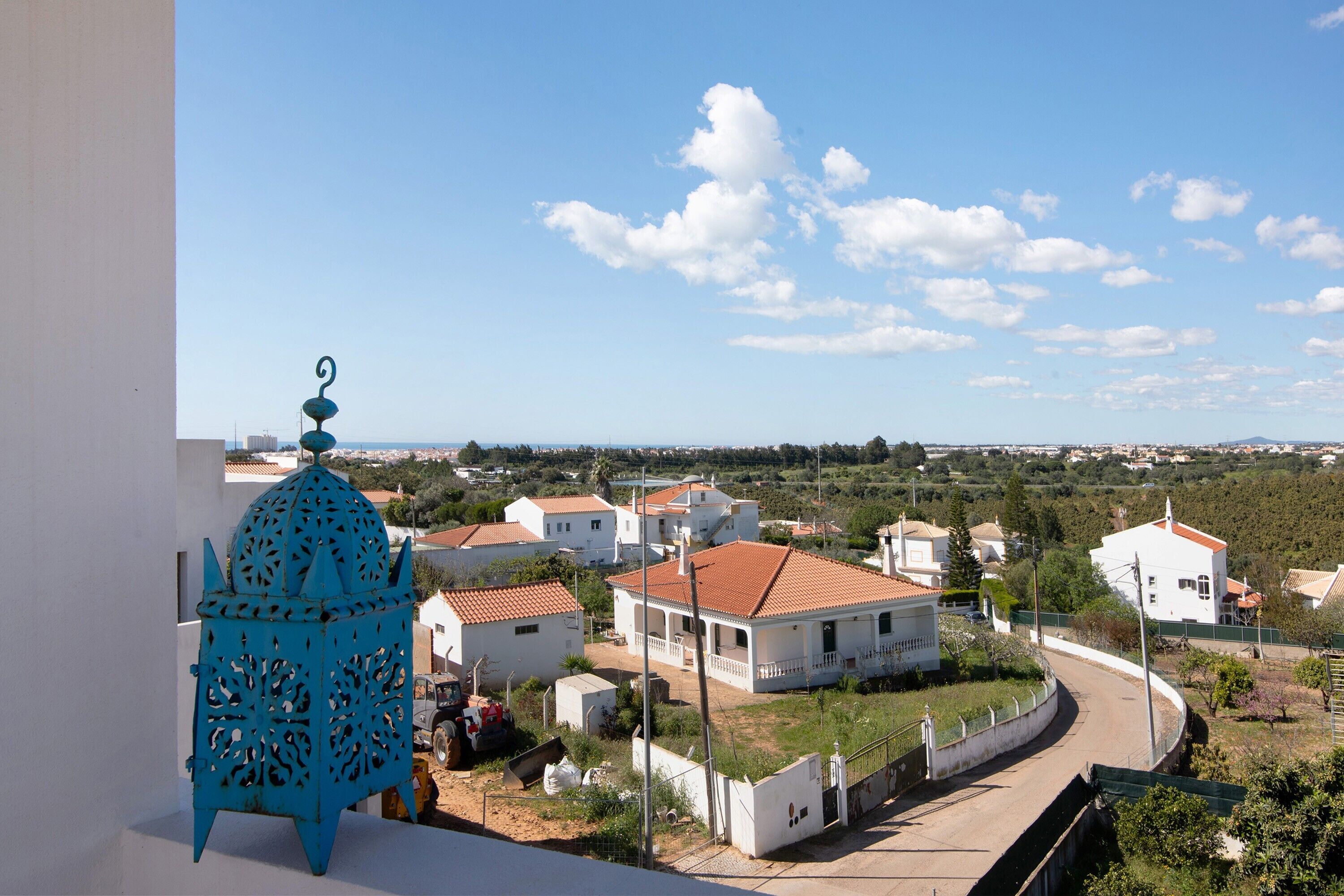Zona residencial con casas blancas, una estructura decorativa azul y cielo despejado.