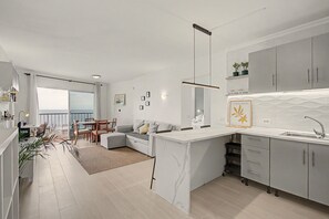 Une cuisine moderne avec un plan de travail en marbre, des meubles gris et une vue sur l’extérieur.