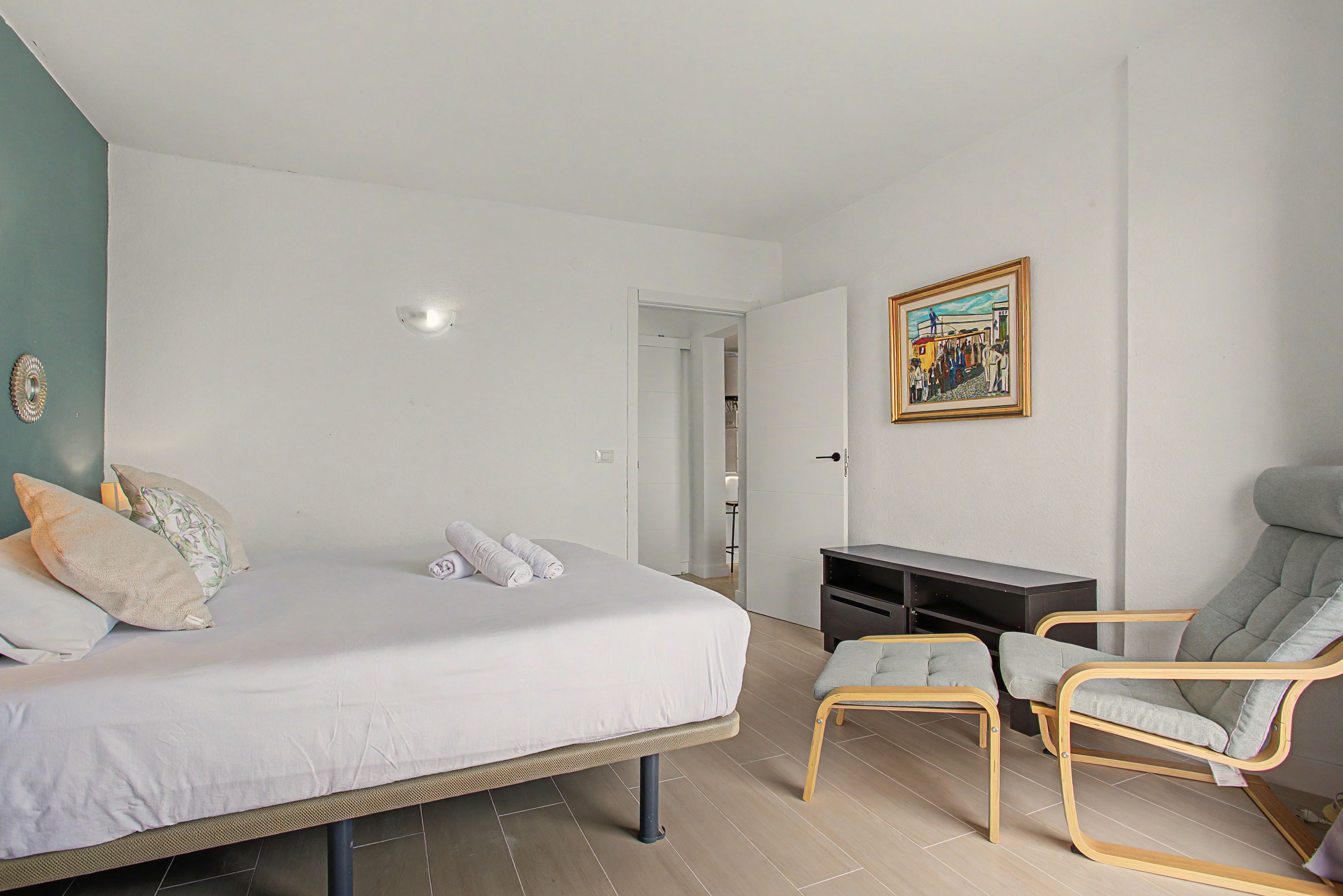 Une chambre à coucher avec un lit, un bureau, une chaise et un tableau accroché au mur.