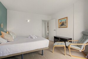 A bedroom with a bed, a desk, a chair, and a painting on the wall.