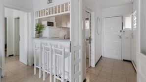 Un interior luminoso con cocina, una mesa de comedor y sillas, y una puerta.