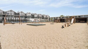 A sandy beach area with playground equipment, a swing set, and a slide. - Holiday apartment near Bønnerup (Glesborg)