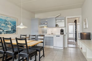 A modern kitchen with a dining area, white cabinetry, and a painting on the wall. - Holiday apartment near Bønnerup (Glesborg)
