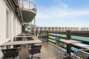 Eine Terrasse mit Tischen und Stühlen mit Blick auf einen Poolbereich.