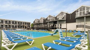 A pool area with blue lounge chairs, a pool, and a building with balconies. - Holiday apartment near Bønnerup (Glesborg)