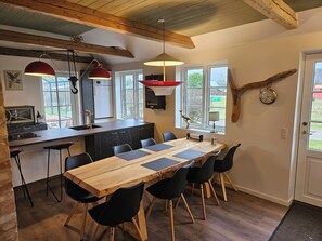 Cozinha moderna com ilha de madeira, cadeiras pretas e iluminação pendente.