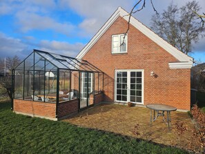 A brick house with a glass greenhouse attached to the side.
