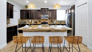A modern kitchen with dark wooden cabinets, a granite countertop, and a central island with bar stools.