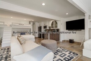 A modern living room with a bunkroom, a flat-screen TV, and a kitchen area.