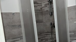 A corner shower enclosure with a glass door, a showerhead, and a handheld shower attachment. - Bed2Go Brescia (Turin)