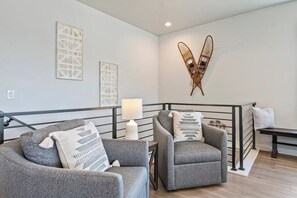 Ein modernes Wohnzimmer mit zwei grauen Sofas, einer Stehlampe und einem dekorativen Wandbild.
