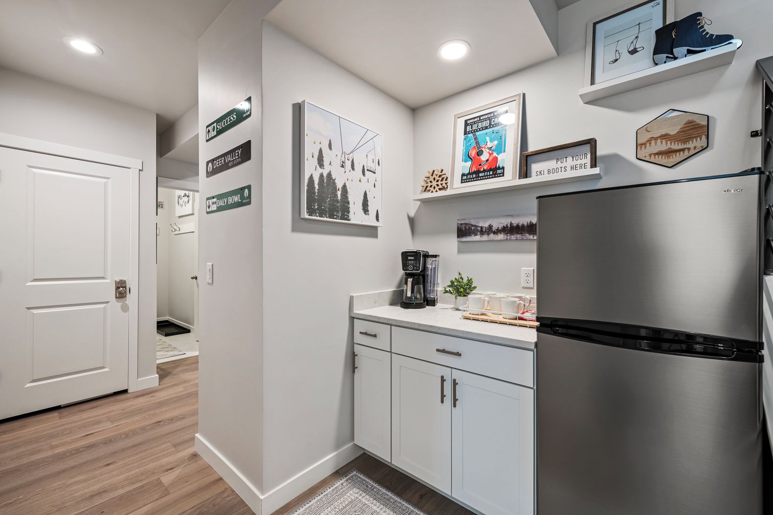 A modern kitchen with a stainless steel refrigerator, white cabinets, and a coffee maker on the counter.