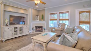 A living room with a fireplace, a television, a ceiling fan, and a sofa. - Spacious 8BR/6BA Duplex with Private Pool – Walk to the Beach – Sleeps 22 (North Myrtle Beach)