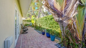 A paved pathway leading to a seating area with chairs and potted plants.