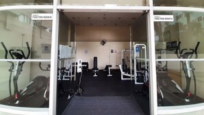 Un gimnàs amb cintes de córrer, màquines de musculació i un mirall.