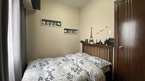 Un dormitori amb llit, armari i paret amb un adhesiu de paisatge urbà.