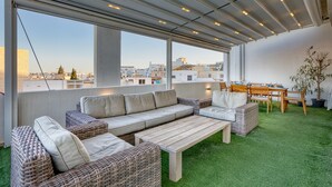 A rooftop terrace with a long sofa, a dining table, and chairs. - Beautiful Penthouse with pool and terrace (Is-Swieqi)