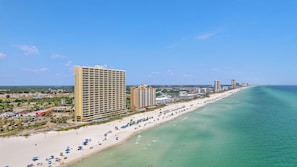 A coastal hotel with multiple floors, a beachside location, and a view of the ocean.