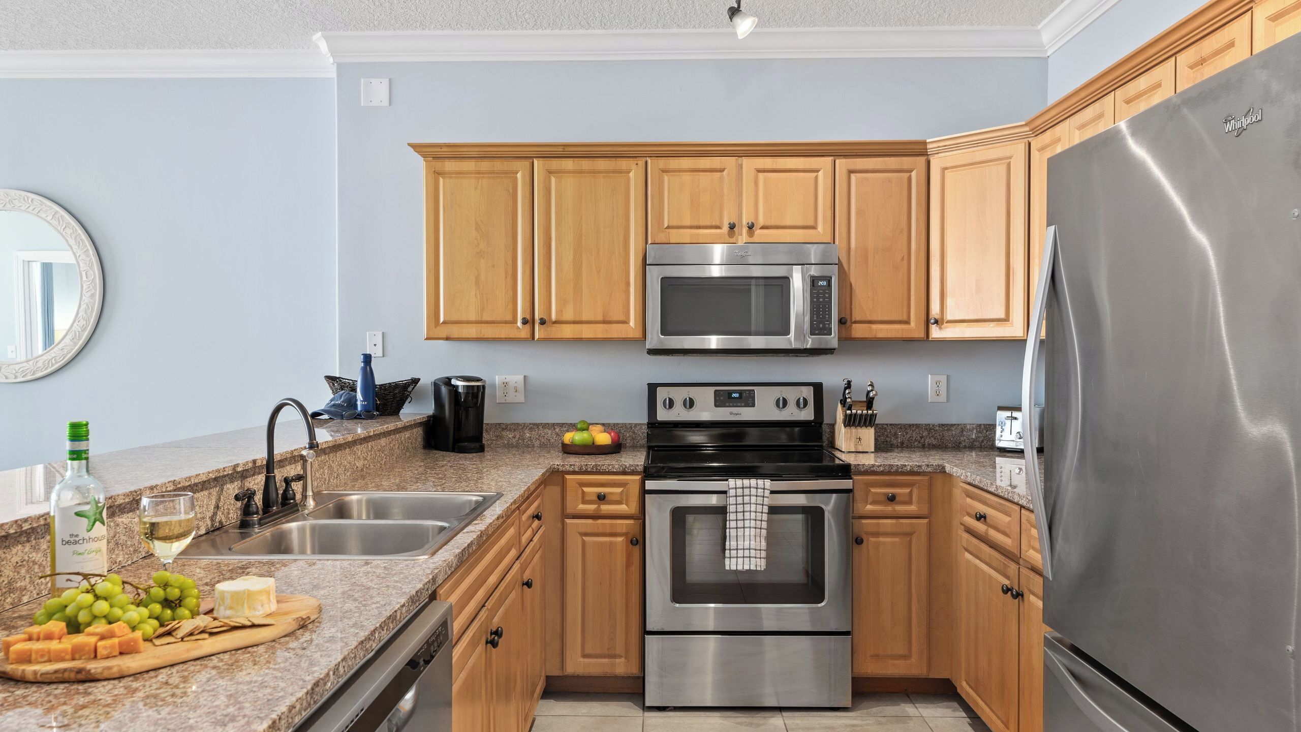 A modern kitchen with wooden cabinets, stainless steel appliances, a granite countertop, and a built-in oven.