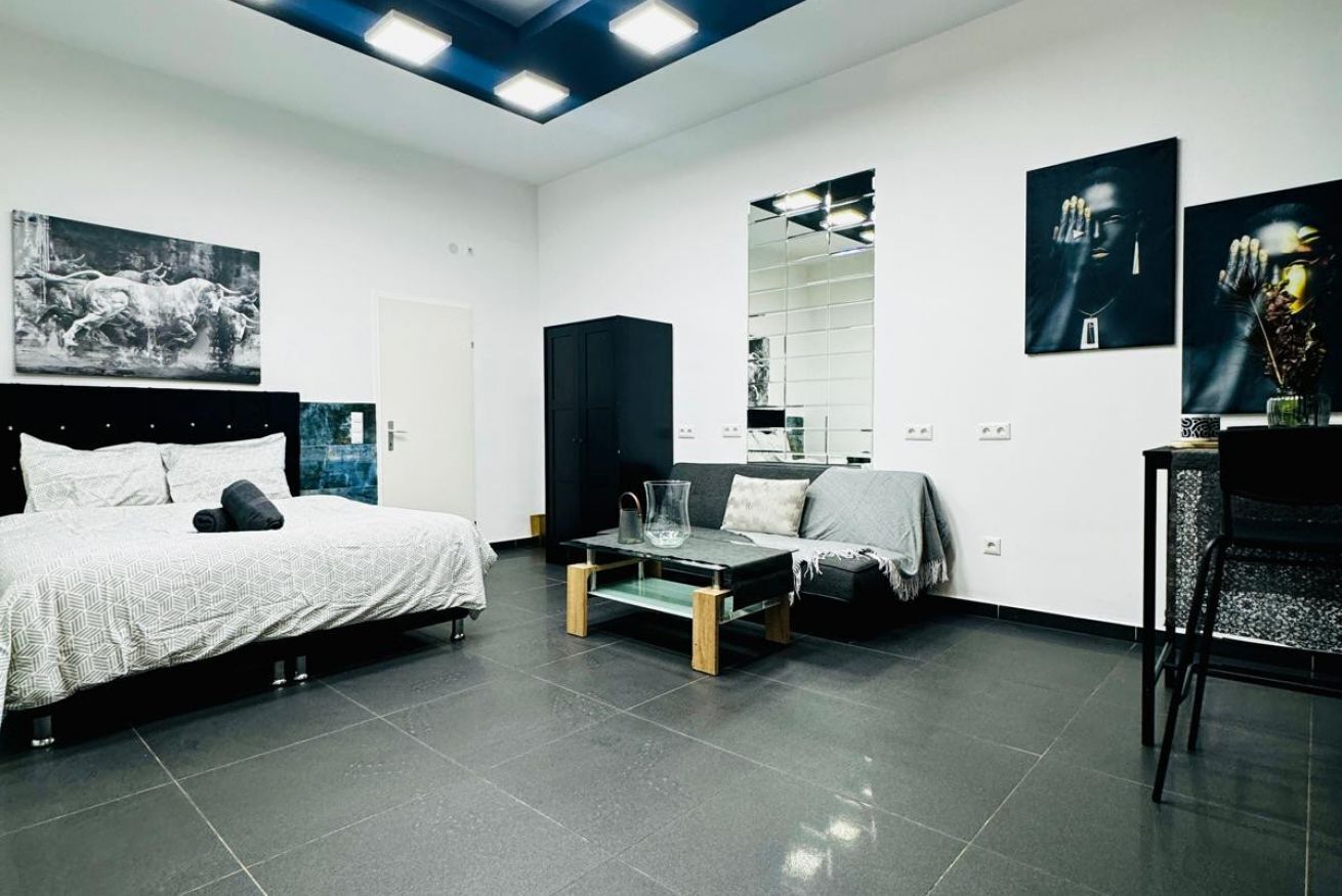 Ein modernes Schlafzimmer mit Bett, einer Couch, einem Couchtisch und Kunstwerken an den Wänden.