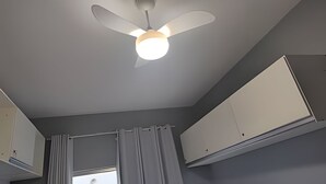 A ceiling fan with a light fixture, a window with curtains, and white cabinets. - Studio Suite Augusta near Av Paulista and Frei Caneca (Sao Paulo)