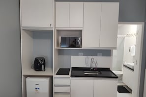 Eine kleine Küche mit Kaffeemaschine, Spüle und Spiegel.
