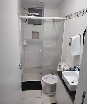 Pieni, käytännöllinen kylpyhuone, jossa on wc, pesuallas ja suihkutila.