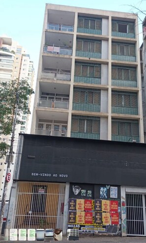 Un edificio de varios pisos con balcones y un escaparate negro con letreros.