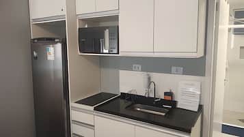 Uma cozinha com geladeira, pia, armários e bancada.