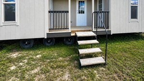 Ett hus på hjul med en liten veranda framtill, en dörr och en liten trappa som leder upp till ingången.