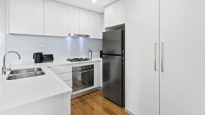 Una cocina moderna con armarios blancos, electrodomésticos de acero inoxidable y piso de madera.