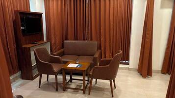 A room with a brown sofa, a small table, and four chairs arranged around it.