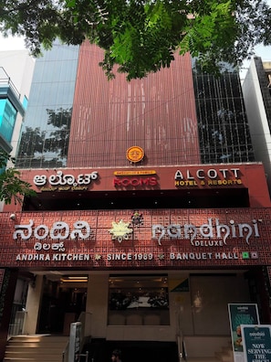 Un hotel con señalización que indica 'ALCOTT HOTEL & RESORTS' y 'ANDHRA KITCHEN'.
